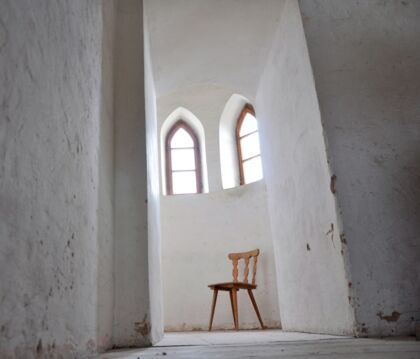 Weißer Kirchengang mit leerem Stuhl. Bild: Christine Immer, pfarrbriefservice.de